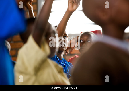 Les enfants lèvent la main avec empressement dans une classe rwandaise. Banque D'Images