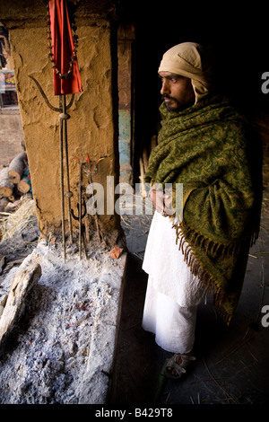 L'un des DOM, un intouchable qui dirige les cérémonies de crémation, maintient la flamme éternelle à l'aube dans la ville de Varanasi. Banque D'Images