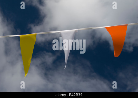 Partie bunting drapeaux de différentes couleurs avec des nuages et ciel bleu en arrière-plan. Banque D'Images