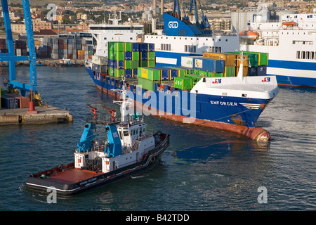 Bateau remorqueur tirant d'un cargo transportant des conteneurs à la mer au Port de Civitavecchia, Italie, le Port de Rome Banque D'Images