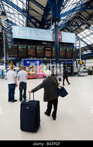 Personnes en attente devant le calendrier des panneaux d'informations sur le grand hall salon de la gare de Brighton East Sussex uk Banque D'Images