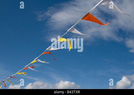 Partie bunting drapeaux de différentes couleurs avec des nuages et ciel bleu en arrière-plan. Banque D'Images