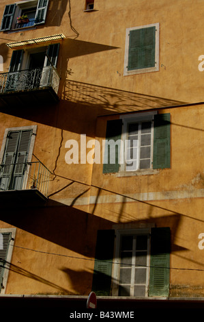 Balcon exprimés tôt le matin des ombres sur les images peintes de fenêtres à volets sur le côté d'un immeuble de la vieille ville de Nice Banque D'Images