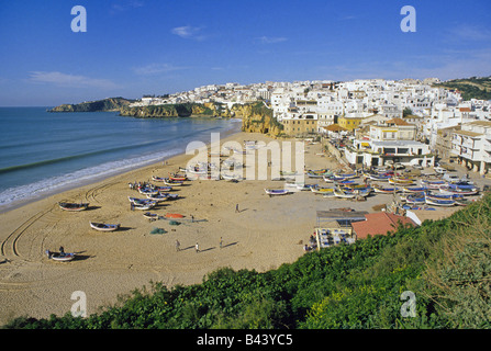 Les pêcheurs tendent leurs filets autour de leurs bateaux sur la plage, dans la ville de pêche Albufeira blanchis Banque D'Images