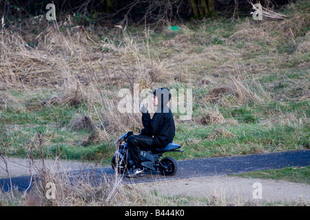 Garçon sur mini moto dans un parc de pays pendant les heures de classe le tabagisme, et vêtu d'un sweat Banque D'Images