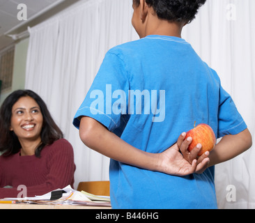 Mixed Race boy apple donnant à l'enseignant Banque D'Images