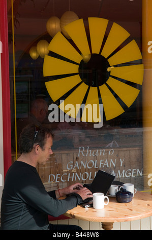 L'homme à l'aide d'un ordinateur portable à l'extérieur de la carrière des vegetarian cafe Machynlleth Powys Pays de Galles UK Banque D'Images