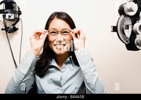 Asian woman putting on eyeglasses Banque D'Images