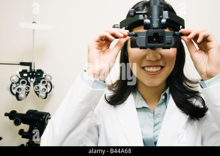Asian female optométriste portant l'équipement d'examen Banque D'Images
