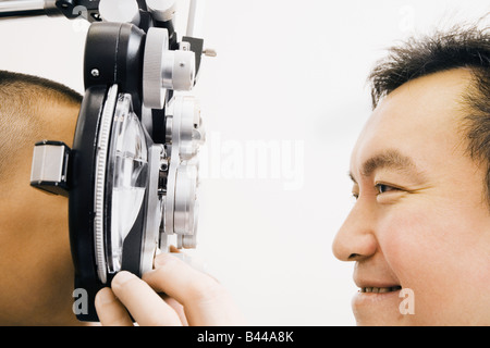 Asian male optometrist examining patient Banque D'Images