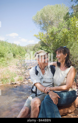 Multi-ethnic senior couple sitting next to stream Banque D'Images