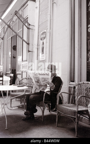 Un homme lit le journal dans un café de la rue Marsaille Banque D'Images