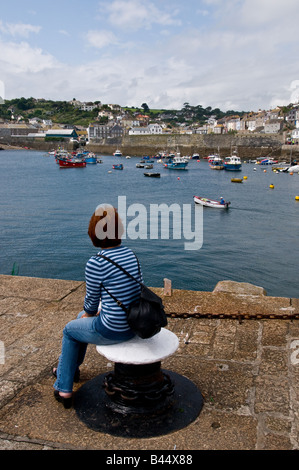 Une femme assise sur le quai à Mevagissey Harbour à Cornwall. Banque D'Images