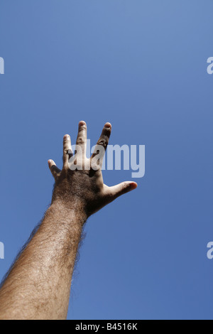 La main de l'homme atteindre dans ciel bleu clair Banque D'Images