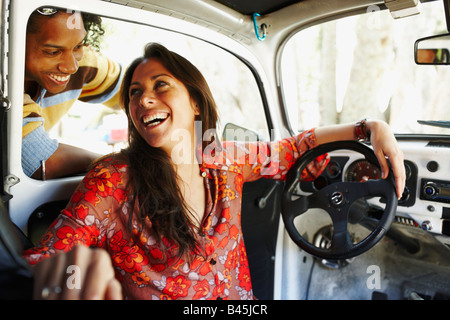 Hispanic woman assis à l'intérieur voiture rire à ami Banque D'Images