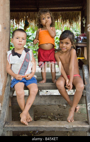 Trois enfants brésiliens qui vivent dans un village par le fleuve Madeira pose devant l'appareil photo à l'entrée de leur maison. Banque D'Images