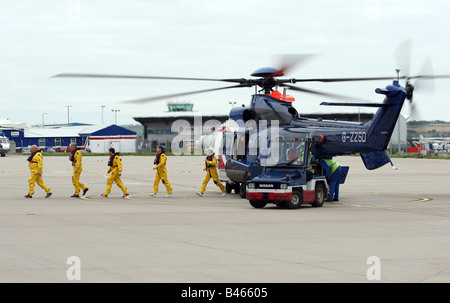 Les travailleurs du pétrole de la mer du Nord au large des côtes dans des combinaisons de survie de descendre un hélicoptère superpuma Bristow à l'aéroport d'Aberdeen, Écosse, Royaume-Uni Banque D'Images