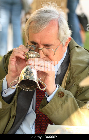 La BBC TV Antiquités Roadshow expert examine de près avec son trophée de la coupe d'argent oculaire loupe Banque D'Images