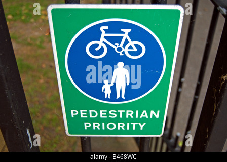 Vert et Bleu signe indiquant la priorité aux piétons sur les cyclistes sur les garde-corps dans Wandsworth park, au sud-ouest de Londres, Angleterre Banque D'Images