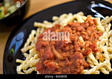 Un délicieux repas italien fait maison pâtes fraîches maison Gemelli avec sauce marinara avec une salade de tomates concombre Banque D'Images