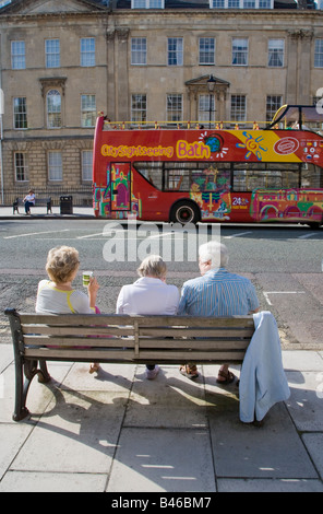 Les personnes ayant un plateau pique-nique sur banc dans street baignoire UK avec baignoire bus de tourisme Banque D'Images