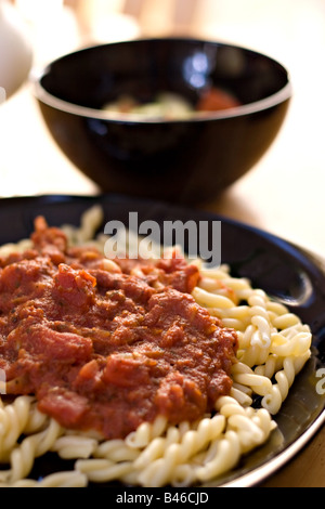 Un délicieux repas italien fait maison pâtes fraîches maison Gemelli avec sauce marinara avec une salade de tomates concombre Banque D'Images