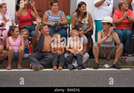 L'Espagnol les enfants assis à regarder la route défilé de chars et les danseurs de Fiesta del Pino in Firgas sur Gran Canaria. Banque D'Images