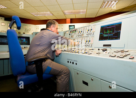 En salopette ingénieur exploite un grand complexe console dans la salle de contrôle de haute technologie d'un UK Power Station Banque D'Images