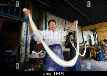 Uyghur Man Making Fresh Laghman le marché du dimanche à nouilles de Kashgar dans la province du Xinjiang en Chine Banque D'Images