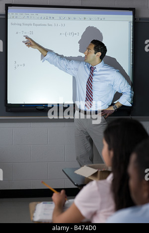 Un enseignant pointant sur des sommes sur un écran de projection Banque D'Images