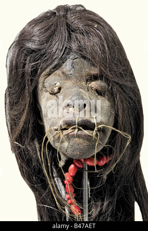 Une tsantsa (tête rétrécie), des Indiens Jivaro, vers 1910 Amérique du Sud, région de la Haute-Amazonie. Les cheveux longs noirs, les yeux et la bouche cousue, le fil manquant dans les endroits. Collier rouge attaché(?). Sur un support métallique avec prise femelle. Contrairement à la croyance largement répandue selon laquelle les tsantsas étaient considérés comme des trophées, ces têtes ont été maintenues hors de la peur et du respect pour les esprits des ennemis tués, dont les esprits de vengeance ont été maintenus captifs par leurs têtes cousues. Historique, historique, 1910, XXe siècle, américain, Amérique, ethnologie, ethnicité, ethnique, objet, objet, Banque D'Images