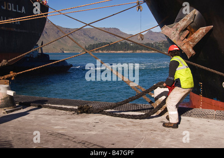 Un manutentionnaire aide à placer les amarres d'un navire qui vient d'arriver au port. Banque D'Images