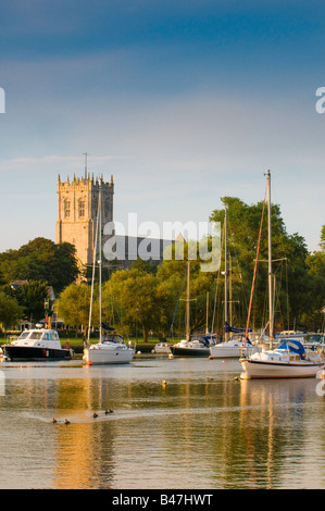 Yachts amarrés dans le coucher de soleil sur la rivière Stour avec Christchurch Priory en arrière-plan dans le Dorset, Angleterre, RU Banque D'Images