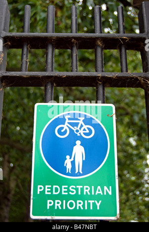 Vert et Bleu signe indiquant la priorité aux piétons sur les cyclistes sur les garde-corps dans Wandsworth park, au sud-ouest de Londres, Angleterre Banque D'Images