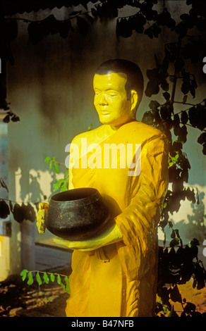 Taille de la vie ensoleillée statue d'un vénéré et rappeler la tenue d'un moine bouddhiste thaïlandais engraved metal bol d'aumône, Temple de Chalong, Phuket, Thailand Banque D'Images