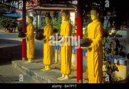 Rangée de soleil, des statues grandeur nature de souvenir vénéré des moines bouddhistes se trouvait sur un socle en pierre holding alms boules à Wat temple de Chalon, Phuket, Thailand Banque D'Images