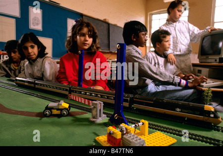 L'enfant regarde un petit train aller en bas de la voie, ses progrès contrôlé par un programme informatique Banque D'Images