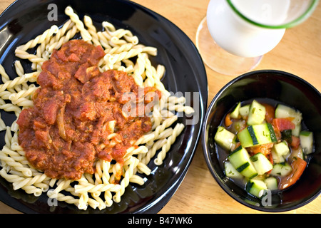 Un délicieux repas italien fait maison pâtes fraîches maison Gemelli avec sauce marinara avec une salade de tomates concombre Banque D'Images