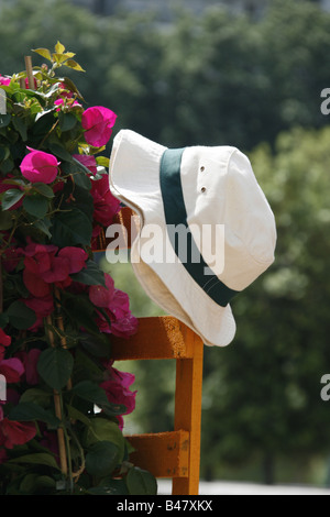 Man's Straw Hat sur jardin clôture avec des fleurs colorées Banque D'Images