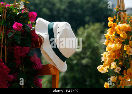 Man's Straw Hat sur jardin clôture avec des fleurs colorées Banque D'Images