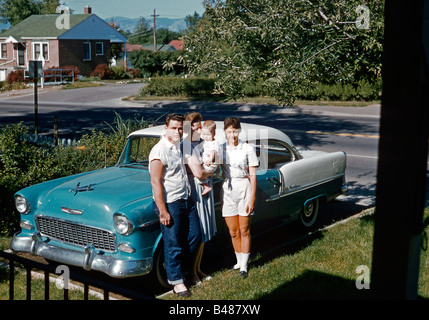 Une famille qui se pose à côté de leur Chevrolet Bel Air garée dans leur allée de banlieue, États-Unis, 1961. Le groupe comprend le bébé du jeune couple. Banque D'Images