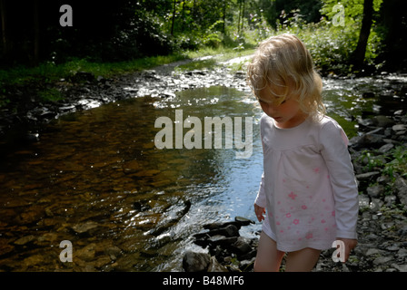 Jeune fille à pied par le Riverside de soleil pommelé Banque D'Images