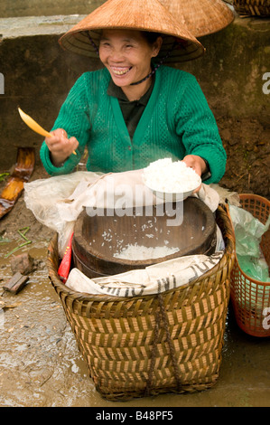 Une femme portant un vendeur de riz chapeau conique en bambou sourit de son pitch à Muong Khuong Vietnam marché Banque D'Images