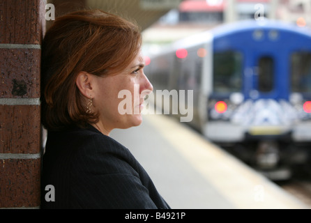 La navette businesswoman maintient occupé en attendant l'arrivée de son train Banque D'Images