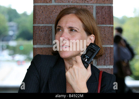 La navette businesswoman maintient occupé en attendant l'arrivée de son train Banque D'Images