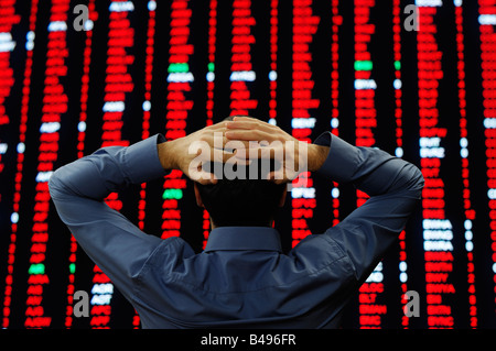 Opérateur en bourse se tenait en face d'un grand affichage des prix des actions Banque D'Images