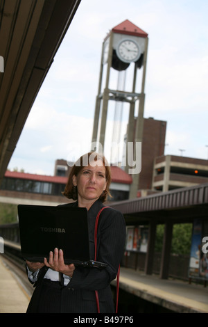 La navette businesswoman maintient occupé en attendant l'arrivée de son train Banque D'Images