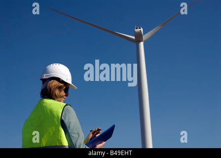 Ingénieur emplois de col vert femelle à côté de la turbine éolienne wind farm Banque D'Images