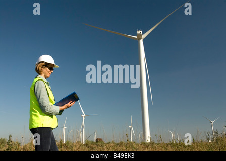 Ingénieur emplois de col vert femelle à côté de la turbine éolienne wind farm Banque D'Images