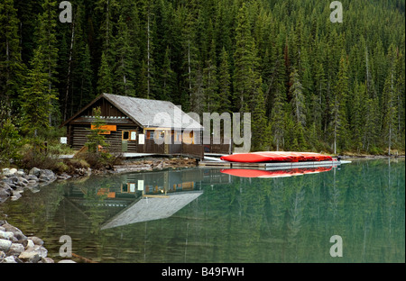 Les canots et rouge location reflétant à Lake Louise, tôt le matin, Banff National Park, Alberta, Canada. Banque D'Images